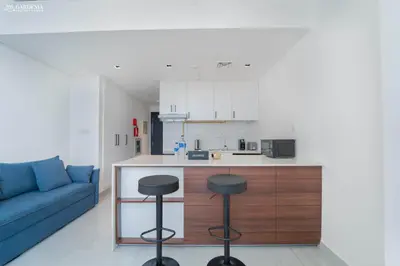 a living room with a couch and a kitchen with stools at O2 Tower JVC, Cozy Home, Peaceful Studio Apartment in Dubai