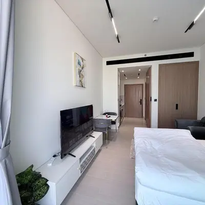 a white room with a bed and a flat screen tv at A place like home for relaxation in Dubai