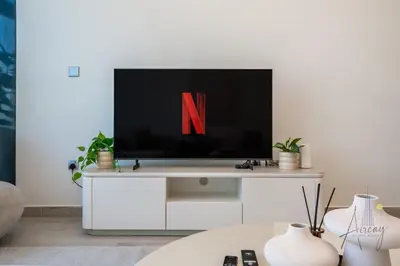 a living room with a tv with the letter n on it at Elegant & Spacious 2-BR Hideaway Riviera Bliss in Dubai
