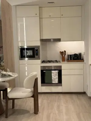 a kitchen with white cabinets and a stove and a table at Palace Residences, Lux 1BR Apartment, Lagoon View in Dubai