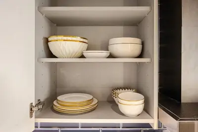 a shelf with bowls and plates in a kitchen at Minutes Walk To Dubai Mall Studio With All Comfort in Dubai