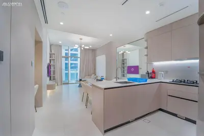 a large kitchen with white counters and a large mirror at Pearl House I JVC- 5 Star Facilities- Magnificent Apartment in Dubai