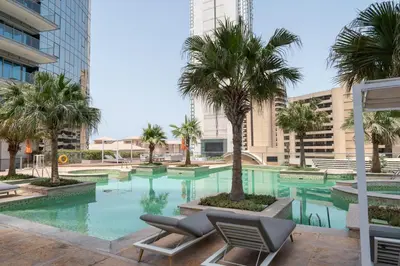 a swimming pool with palm trees and lounge chairs at TRIDENT GRAND JBR I BEACHFRONT 2-Bedroom Apartment I Beautiful Palm and Ocean Views I Amazing Balcony Space in Dubai