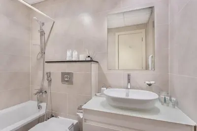 a bathroom with a sink and a toilet and a mirror at Sky-High Luxury Studio Overlooking Trump Golf Club-Carson A, DAMAC Hills, Dubai in Dubai