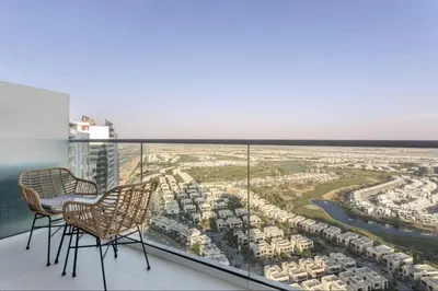 a balcony with two chairs and a view of a city at Sky-High Luxury Studio Overlooking Trump Golf Club-Carson A, DAMAC Hills, Dubai in Dubai