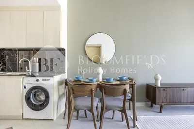 a kitchen with a table with chairs and a washing machine at 202-Bloomfields Iconic 1br Binghatti Avenue in Dubai