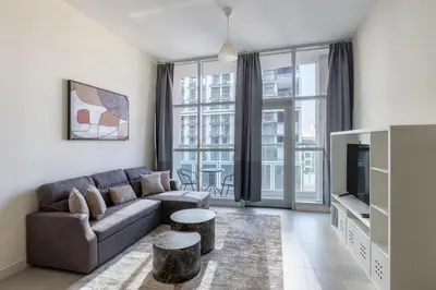 a living room with a couch and a tv at Bright & Modern 1BR La Rivera Apartments, JVC in Dubai