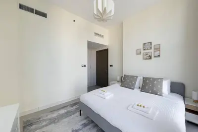 a bedroom with a white bed and a chandelier at Bright & Modern 1BR La Rivera Apartments, JVC in Dubai