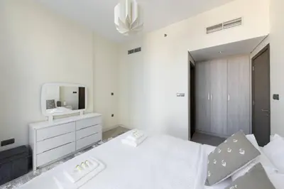 a white bedroom with a white bed and a mirror at Bright & Modern 1BR La Rivera Apartments, JVC in Dubai