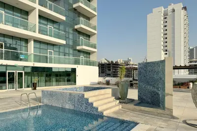 a swimming pool in front of a building at Bright & Modern 1BR La Rivera Apartments, JVC in Dubai