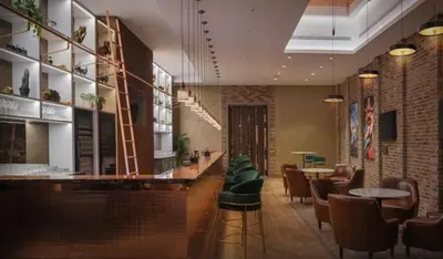 a restaurant with a bar with green chairs and tables at Paramount Midtown Luxury 2BR Sleeps 7 Near Business Bay Metro and Dubai Mall in Dubai