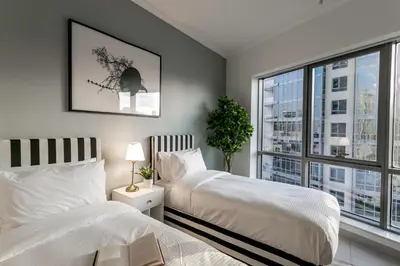 a bedroom with two beds and a large window at La Dolce Vita in Dubai
