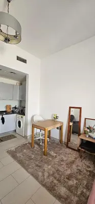 a living room with a table and a kitchen at Peace Home in Dubai