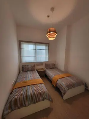 a bedroom with two beds and a chandelier at Bright 2BR Apartment 5-Min Walk to Metro & Mall 1124 in Dubai