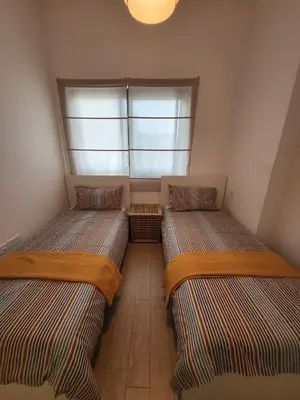 two beds in a small room with a window at Bright 2BR Apartment 5-Min Walk to Metro & Mall 1124 in Dubai