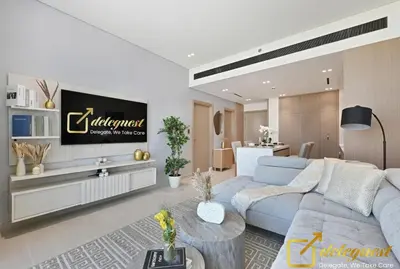 a living room with a blue couch and a tv at Bright 1BR Apartment in Binghatti Phoenix High-Floor Views in Dubai