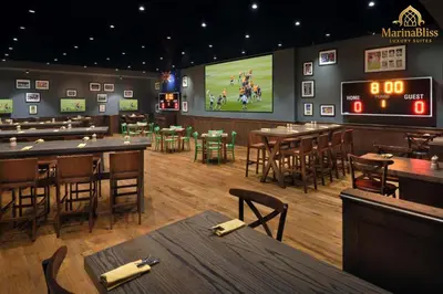a restaurant with tables and a football game on a screen at Deluxe 5 stars Suite - JW Marriott-Marina Mall - Once you see it, you book it! in Dubai
