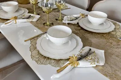 a table set with white dishes and gold napkins at Ultra-luxury 2BHK apartment Stunning Burj Khalifa & Fountain view in Dubai