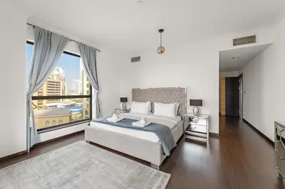 a bedroom with a large bed and a large window at VayK - Spacious 3BR in JBR with Beach Access in Dubai