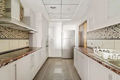 a kitchen with white cabinets and a refrigerator at VayK - Spacious 3BR in JBR with Beach Access in Dubai