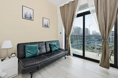 a black leather couch in a living room with a window at Dubai JVC - Oxford Residence 2 - Parking&Balcony in Dubai