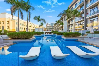 a swimming pool at a resort with lounge chairs and palm trees at Dubai JVC - Oxford Residence 2 - Parking&Balcony in Dubai