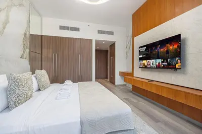 a bedroom with a large bed with a tv on the wall at 3BR with Burj Khalifa View - Pool - Gym - Downtown in Dubai
