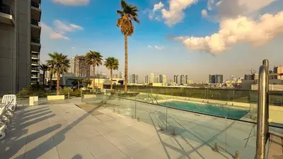 a swimming pool with a palm tree on top of a building at Skyline View Stu 20th Floor Regina Tower, JVC in Dubai