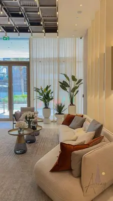 a living room with a couch and tables and plants at Cosy Corner 1BR Designer Apt Luxe Nest in JVC in Dubai