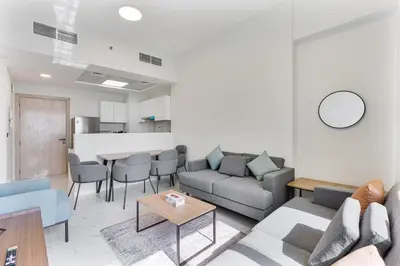 a living room with a couch and a table at Cozy 1BR Apartment, 20 Min to Jebel Ali Beach in Dubai
