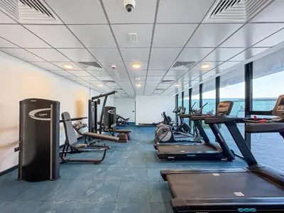 a gym with treadmills and elliptical machines at Cozy 1BR Apartment, 20 Min to Jebel Ali Beach in Dubai