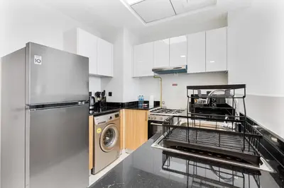 a kitchen with a refrigerator and a dishwasher at Cozy 1BR Apartment, 20 Min to Jebel Ali Beach in Dubai