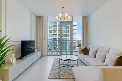 a living room with a white couch and a tv at Cozy 1BR at D1 Residence 13 with Stunning City View in Dubai