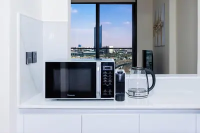 a microwave sitting on a counter in a kitchen with a window at Stylish JVC Apt with Pool & Gym in Sabkhah