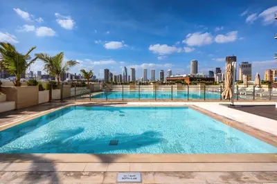 a swimming pool with a city skyline in the background at Stylish JVC Apt with Pool & Gym in Sabkhah