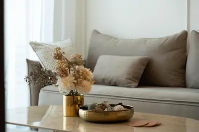 a coffee table with a vase of flowers and a couch at Luxury 1BR Apartment - Pool View - The Crest Dubai in Dubai