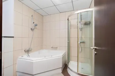 a bathroom with a shower and a white bath tub at The Jewel Tower 2 in Dubai