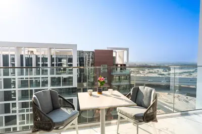 a balcony with a table and chairs on a building at Cozy Apartment in Azizi Riviera - 10 min to Burj Khalifa in Dubai