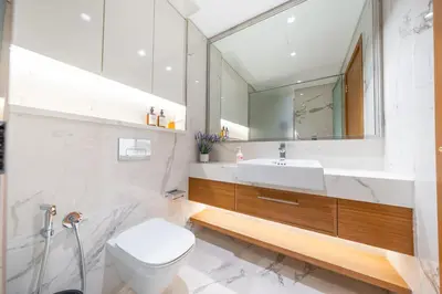a bathroom with a toilet and a sink and a mirror at Cozy Apartment in Azizi Riviera - 10 min to Burj Khalifa in Dubai