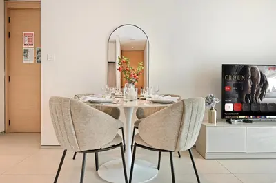 a dining room with a table with chairs and a mirror at Brand New 1BD in Address JBR, Relaxing Stay for 2 in Dubai