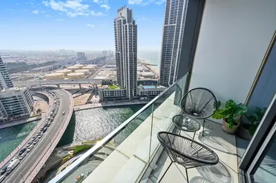 a balcony with two chairs and a view of a city at Brand New 1BD in Address JBR, Relaxing Stay for 2 in Dubai