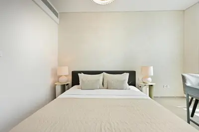 a bedroom with a large white bed with two lamps at Brand New 1BD in Address JBR, Relaxing Stay for 2 in Dubai