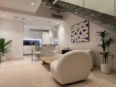 a living room with a couch and chairs and a kitchen at Sterling West House in Dubai