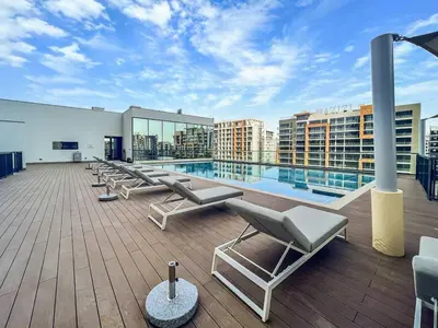 a rooftop deck with lounge chairs and a swimming pool at Vogue Al Maktoum City Sobha Hartland Waves Near to Downtown, Burj Khalifa and Dubai Mall, One Bedroom Apartment plus Kids room with Balcony and City View, Access to all Amenities in Dubai