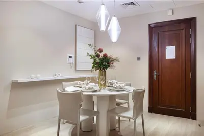 a white dining room with a table and chairs at Luxury Old Town Yansson Downtown Dubai Apartment Pool Burj Khalifa Views Steps to Dubai Mall by La Brisa in Dubai