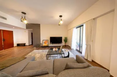 a living room with a couch and a tv at Lux 4BR JBR I Sea View I Walk to Beach I Sleeps 12 in Dubai