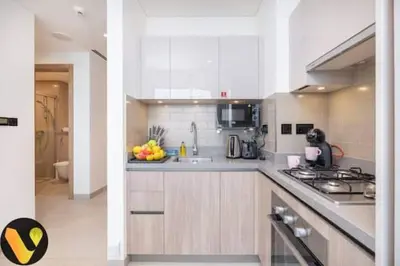 a white kitchen with a bowl of fruit on the counter at Vogue Al Maktoum City Sobha Hartland Waves Near to Downtown, Burj Khalifa and Dubai Mall, One Bedroom Apartment plus Kids room with Balcony and City View, Access to all Amenities in Dubai