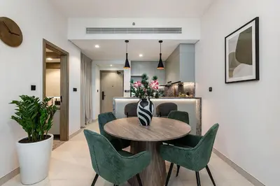 a dining room with a table and green chairs at Stylish 1BR Apartment at Damac Hills Golf Gate in Dubai