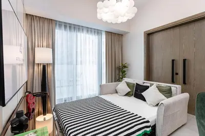 a bedroom with a bed and a large window at Stylish 1BR Apartment at Damac Hills Golf Gate in Dubai