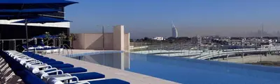 a swimming pool with blue lounge chairs and umbrellas at Prestige Heights 1BR with Iconic Oceanview in Dubai